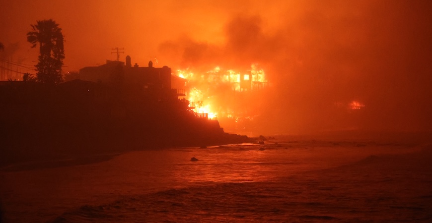 Flames, the beach and the ocean are depicted in a scene from the January 2025 Palisades fire.